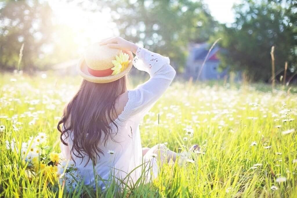 Foto de uma mulher de branco, e com chapéu, no campo, representando a liberdade que se tem ao empreender via internet