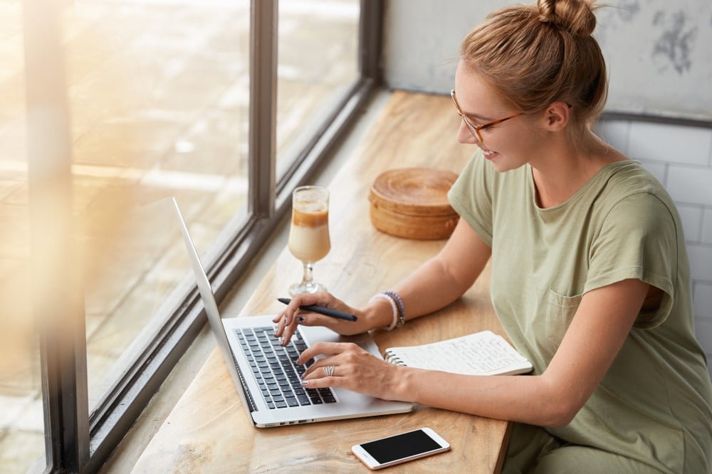 Foto de uma mulher feliz no seu trabalho pela Internet em um notebook